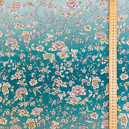 Floral patterned fabric with a ruler for scale on a teal background